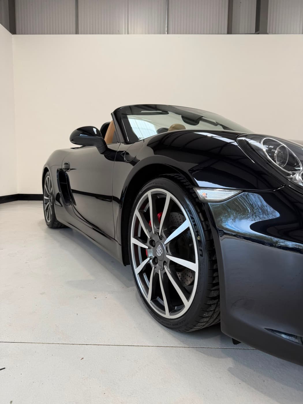 A black Porsche detailed to a mirror finish in the studio